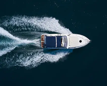 Overhead view of a motorboat moving through dark blue water, leaving a white wake behind.